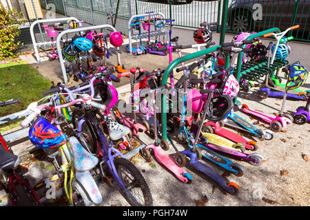 September 2017 - Kinder Fahrräder und Motorroller in der Schule Eingang in England, UK geparkt; Kinder und Eltern werden ermutigt, zum Spazieren gehen und Rad zu verringern Stockfoto