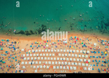 Antenne top Aussicht auf den Strand. Menschen, Schirme, Sand und Meer Wellen Stockfoto