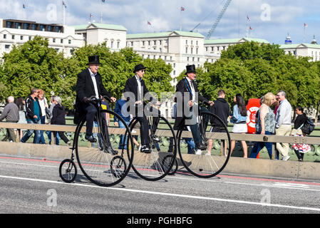 Drei Penny Farthing Radfahrer Fahrt über die Westminster Bridge, London, UK. Herren Reiter. Penny farthings von UDC, Einrad dot com. Top Hüte Stockfoto