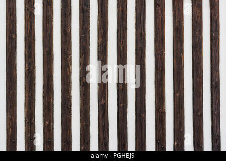 Kontrastierende gestreifte Textur. Dekorative Holz Latten. Weiß gestrichenen Wand mit senkrechten Streifen von alten, braunen geknotet Planken. Ursprüngliche Holz- Hintergrund. Stockfoto