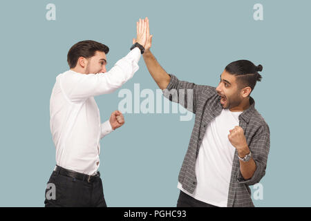 Ja haben wir. Ausdruck Profil Seitenansicht von zwei jungen gutaussehenden glücklich zufrieden Bärtigen partner Triumph feiern gemeinsam, was Hi fünf Hände. ind Stockfoto