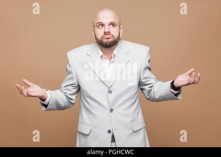 Ich weiß nicht! Portrait von verwirrt kreuzte die Hände schön im mittleren Alter kahl bärtigen Geschäftsmann in Classic Light grauen Anzug stehen und die Pflege von Denken. Stockfoto
