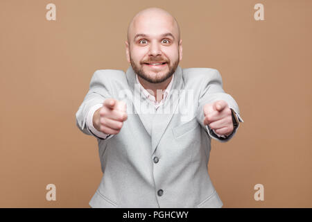 Ich kenne sie. Portrait von Stattlichen im mittleren Alter kahl bärtigen Geschäftsmann in Classic Light grauen Anzug stehen, zeigen und auf Kamera mit Smiley Stockfoto