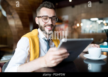 Portrait von fröhlichen moderne Geschäftsmann mit digitalen Tablet an der Theke sitzen im Cafe Stockfoto