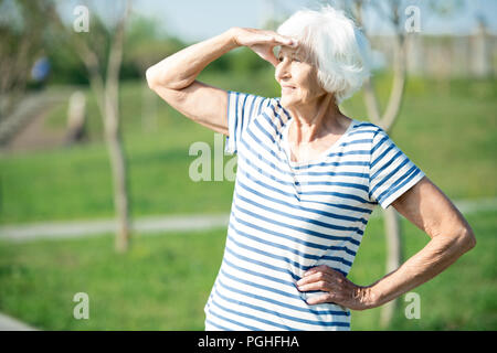 Taille bis Portrait von Active Senior Frau weg suchen Abschirmung Augen aus Sonnenlicht im Freien Platz kopieren Stockfoto