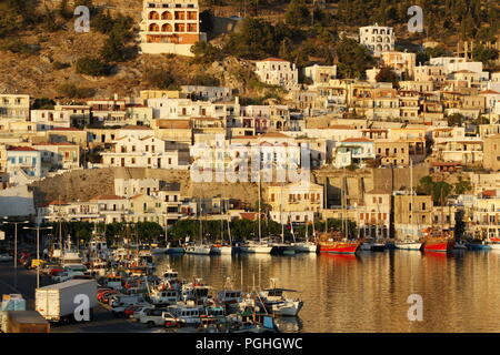 Griechenland, Europa, der Insel Kalymnos. Die Fähre ist über zu segeln und von der Terrasse aus ist der Hafen in einem weichen Sommer am frühen Morgen Licht getaucht Stockfoto