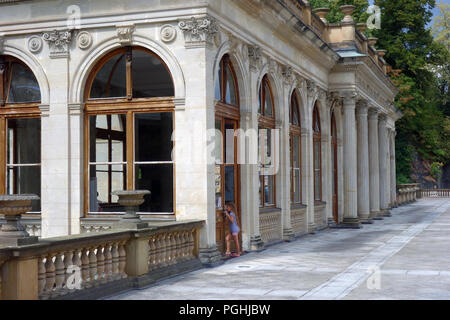 Junge Mädchen beim Blick durch das Fenster der Mühlenkolonnade Gebäude in der Kurstadt Karlovy Vary (Karlsbad) in Westböhmen Region der Tschechischen Republik Stockfoto