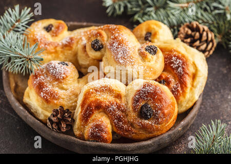 Traditionelle schwedische Weihnachten Safran Brötchen (lussebulle oder lussekatt). Schwedische Weihnachten. Dunkler Hintergrund, Weihnachtsdekoration. Stockfoto