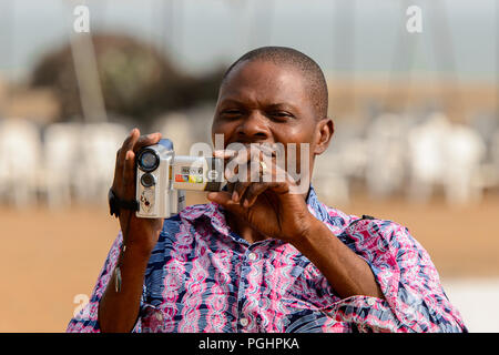 OUIDAH, BENIN - Jan 10, 2017: Unbekannter beninischen Mann mit Videokamera an der voodoo Festival, das jährlich im Januar gefeiert wird, 10. Stockfoto