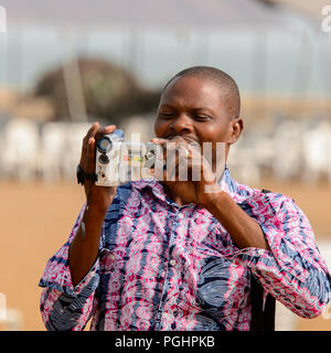 OUIDAH, BENIN - Jan 10, 2017: Unbekannter beninischen Mann mit Videokamera an der voodoo Festival, das jährlich im Januar gefeiert wird, 10. Stockfoto