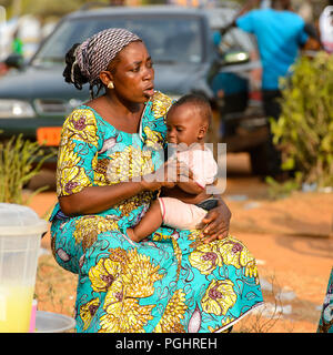 OUIDAH, BENIN - Jan 10, 2017: Unbekannter beninischen Frau hält Ihr Baby an den lokalen Markt. Benin Menschen leiden unter der Armut wegen der schlechten Konjunktur Stockfoto