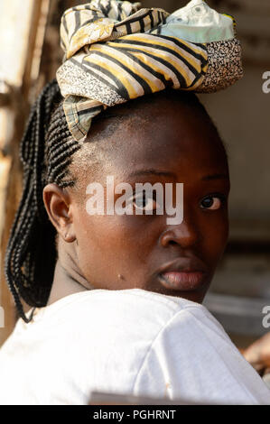 OUIDAH, BENIN - Jan 10, 2017: Unbekannter beninischen Frau mit Zöpfen schaut sich um auf dem lokalen Markt. Benin Menschen leiden unter der Armut aufgrund der schlechten Stockfoto