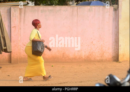 OUIDAH, BENIN - Jan 10, 2017: Unbekannter beninischen Frau im gelben Kleid geht auf die Straße. Benin Menschen leiden unter der Armut wegen der schlechten Konjunktur Stockfoto