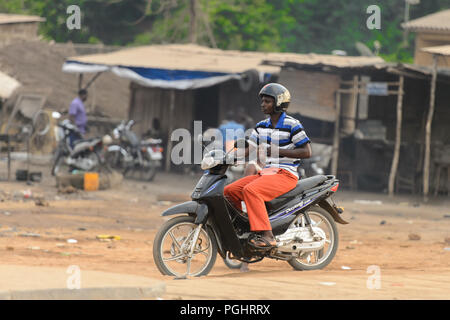 OUIDAH, BENIN - Jan 10, 2017: Unbekannter beninischen Mann reitet ein Motorrad. Benin Menschen leiden unter der Armut wegen der schlechten Konjunktur Stockfoto