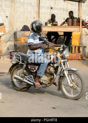OUIDAH, BENIN - Jan 10, 2017: Unbekannter beninischen Mann reitet ein Motorrad. Benin Menschen leiden unter der Armut wegen der schlechten Konjunktur Stockfoto