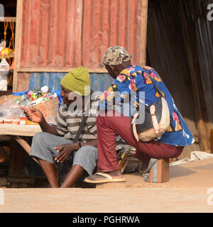 OUIDAH, BENIN - Jan 10, 2017: Unbekannter beninischen Männer sitzen auf der Straße. Benin Menschen leiden unter der Armut wegen der schlechten Konjunktur Stockfoto