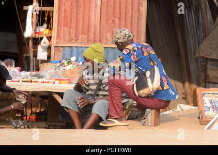 OUIDAH, BENIN - Jan 10, 2017: Unbekannter beninischen Männer sitzen auf der Straße. Benin Menschen leiden unter der Armut wegen der schlechten Konjunktur Stockfoto