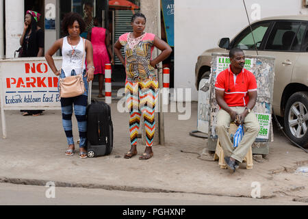 Zentrale Region, GHANA - Jan 17, 2017: Unbekannter Ghanaischen zwei Frauen stehen neben der Straße mit Gepäck in lokalen Dorf. Menschen in Ghana Leiden von p Stockfoto