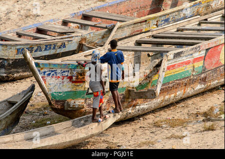 ELMINA, GHANA - Jan 18, 2017: Unbekannter Ghanaischen zwei Männer in bunten Gewändern von hinter dem Stand in der Nähe der Boote aus Holz in Elmina Port. Menschen in Ghana Stockfoto