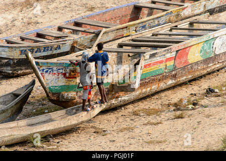 ELMINA, GHANA - Jan 18, 2017: Unbekannter Ghanaischen zwei Männer in bunten Gewändern von hinter dem Stand in der Nähe der Boote aus Holz in Elmina Port. Menschen in Ghana Stockfoto