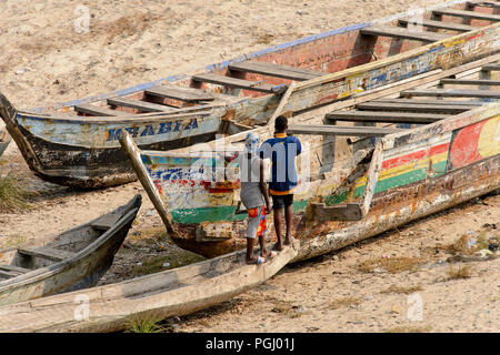 ELMINA, GHANA - Jan 18, 2017: Unbekannter Ghanaischen zwei Männer in bunten Gewändern von hinter dem Stand in der Nähe der Boote aus Holz in Elmina Port. Menschen in Ghana Stockfoto