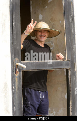 ELMINA, GHANA - Jan 18, 2017: Unbekannte europäische Tourist in einen Hut zeigt zwei Finger und lächelt in Elmina. Stockfoto