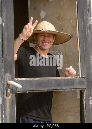 ELMINA, GHANA - Jan 18, 2017: Unbekannte europäische Tourist in einen Hut zeigt zwei Finger und lächelt in Elmina. Stockfoto