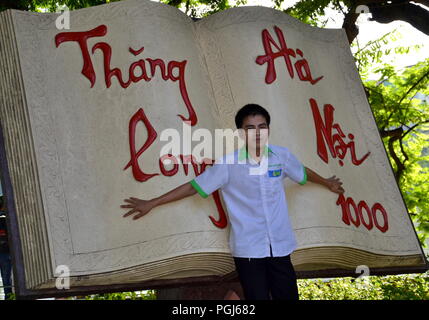 Ein Junge posiert mit einer riesigen Buchskulptur, die den 1000th. Jahrestag der Gründung von Hanoi feiert, neben dem Hoan Kiem See, Hanoi, Vietnam. Stockfoto