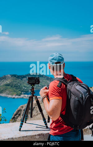 Männliche Fotografen mit Rucksack genießen Aussicht nach Assos Dorf während der Aufnahme Bild von oben View Point. Kamera auf Stativ Stockfoto