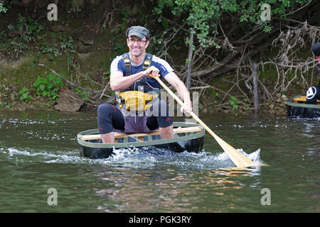 Shropshire, Großbritannien. 27. August 2018. Wettbewerber in den jährlichen August Bank Holiday Coracle Rennen auf dem Fluss Severn in Ironbridge in Shropshire. Diese kleinen handgebaut Fluss haben auf Flüssen in Großbritannien seit Hunderten von Jahren verwendet und die ironbridge Rassen haben für viele Jahre gehalten worden. Stockfoto