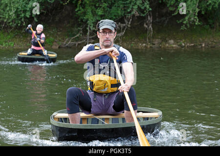 Shropshire, Großbritannien. 27. August 2018. Wettbewerber in den jährlichen August Bank Holiday Coracle Rennen auf dem Fluss Severn in Ironbridge in Shropshire. Diese kleinen handgebaut Fluss haben auf Flüssen in Großbritannien seit Hunderten von Jahren verwendet und die ironbridge Rassen haben für viele Jahre gehalten worden. Stockfoto