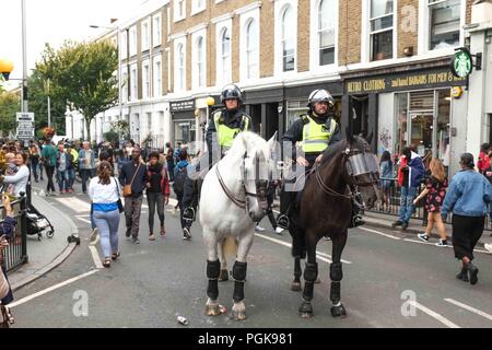 London, Großbritannien. 27. August 2018. Eine Dame und Kind haben ihre Foto neben zwei Polizei Pferde in Notting Hill Carnival Parade in London. Credit: Claire Doherty/Alamy leben Nachrichten Stockfoto