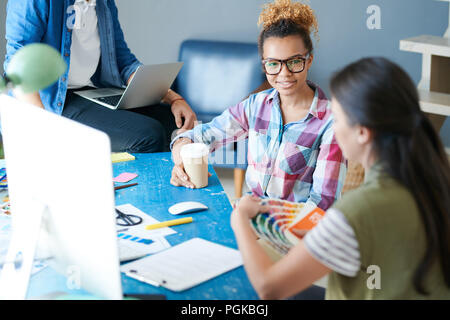 Porträt des zeitgenössischen afroamerikanischen Frau diskutieren kreatives Projekt mit Kollegen am Schreibtisch im Büro sitzen, Platz kopieren Stockfoto