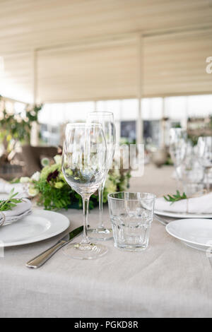 Hochzeit oder Gala Dinner. Die Tische und Stühle für Gäste, serviert mit Besteck und Geschirr. Mit einem Leinen Tischdecke Läufer abgedeckt. Party auf der Terrasse Stockfoto
