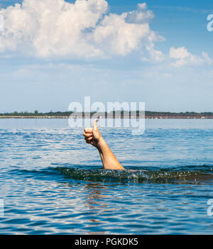 Die Hand des Mannes Sticks aus dem Wasser heraus und zeigt eine Geste, Sommer Tag Stockfoto