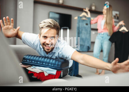 Mann liegt auf überfüllten Koffer, überfüllt oder überladen Koffer. Die Gebühren für die Reise. Gepäck Vorbereitung Stockfoto