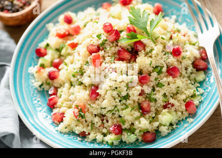 Tabbouleh Salat mit Granatapfel Samen auf Türkis Platte. Detailansicht. Gesunde vegetarische arabisch Salat Stockfoto