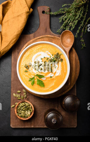 Kürbis Suppe in der Schüssel, garniert mit Sahne und Kürbiskernen. Ansicht von oben. Herbst Herbst Komfort Essen. Creme von Kürbis Kürbis Suppe Stockfoto