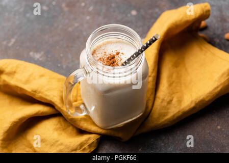 Banane protein Smoothie oder Milchshake gekrönt mit Zimt auf gelber Senf Farbe Textil. Ansicht von oben, selektive konzentrieren. Gesunder Lebensstil, Fitness, spor Stockfoto