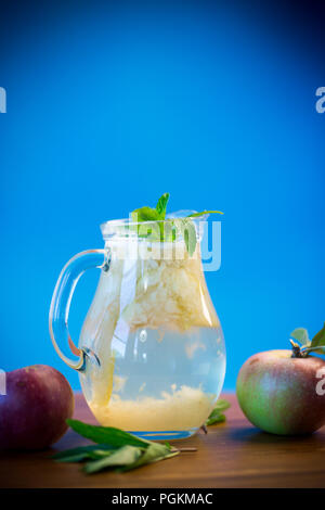 Süßes kaltes Kompott von frischen Äpfeln mit einem Zweig Minze im Glas Dekanter Stockfoto