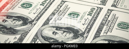 Die stückelungen von einhundert Dollar sind in einer Reihe angeordnet. Glühen in der Ecke. Anzeigen in einem Winkel. Stockfoto