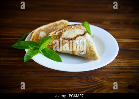 Dünne Süße Pfannkuchen in der Form eines Dreiecks mit einem Zweig Minze in eine Platte auf einem Holztisch gefaltet Stockfoto