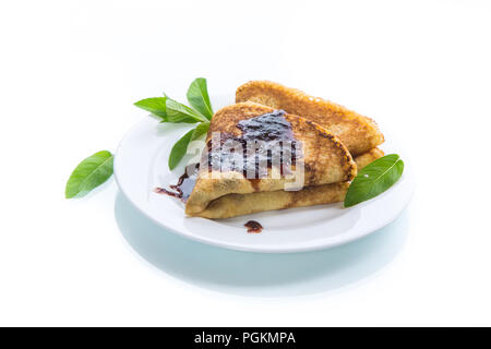 Dünne Süße Pfannkuchen in der Form eines Dreiecks mit Marmelade und einem Zweig Minze in eine Platte auf einem weißen Hintergrund gefaltet Stockfoto