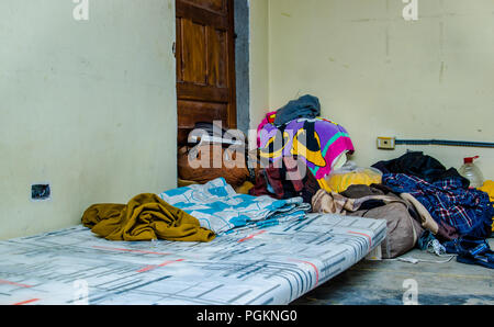 QUITO, Ecuador, 21. AUGUST 2018: Haufen bunte Kleidung, Taschen und Accessoires im Boden von einem Zimmer in ein Refugium für Menschen, die esca Stockfoto