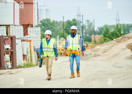 In voller Länge Porträt von zwei Bauarbeiter tragen hardhats gehen über Website, kopieren im freien Raum Stockfoto