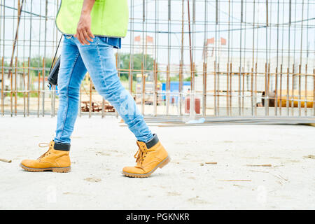 Niedrige Abschnitt Portrait von unkenntlich worker Jeans und Stiefel Kreuzung Baustelle, kopieren Raum Stockfoto