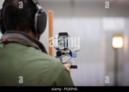 Ein blinder Mann hat das Ziel, einen speziell ausgestatteten Gewehr auf das Ziel einer wettbewerbsfähigen Schießstand. Stockfoto