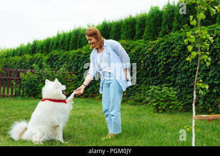 Stilvolle blonde Frau mit Hund im Garten Stockfoto