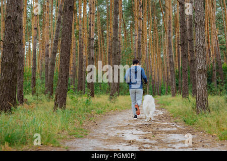 Dunkelhaarige Mann in den Wald mit seiner weißen pet Stockfoto
