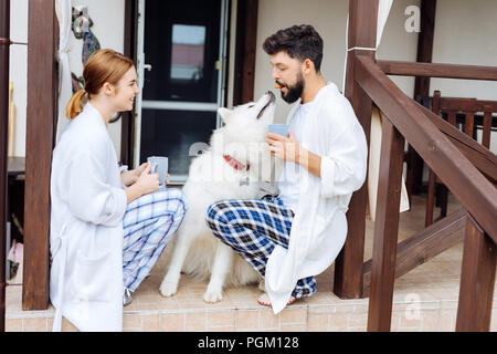 Strahlendes paar Spaß mit ihren weißen Hund am Morgen Stockfoto